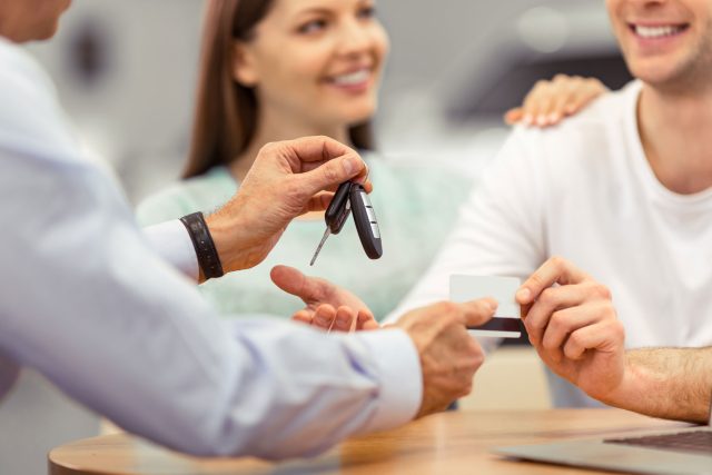 a man handing a car key to a woman.