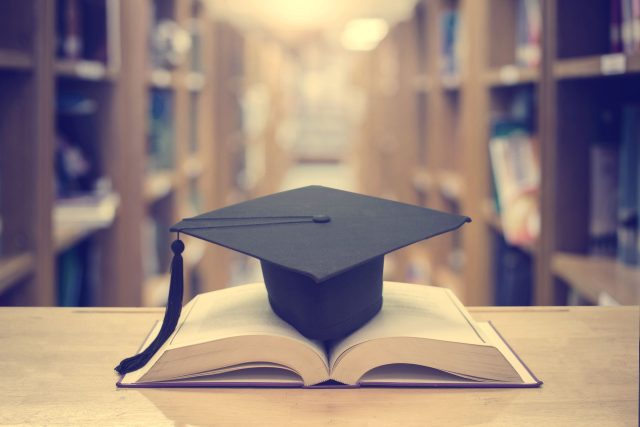 a book with a graduation cap on top of it.